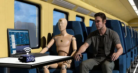 BeanDevice AX-3D Xrange wireless vibration sensor on a table or chair, in a train, connected to BeanScape Willow software during ride comfort vibration tests with a mannequin and an engineer inside a railway train.